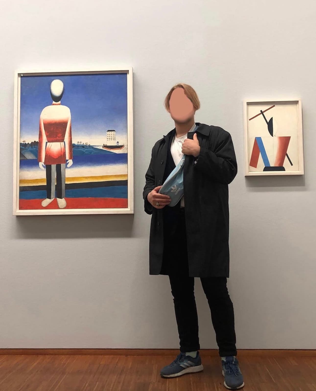 Hlib Dovzhuk standing between two paintings in a gallery