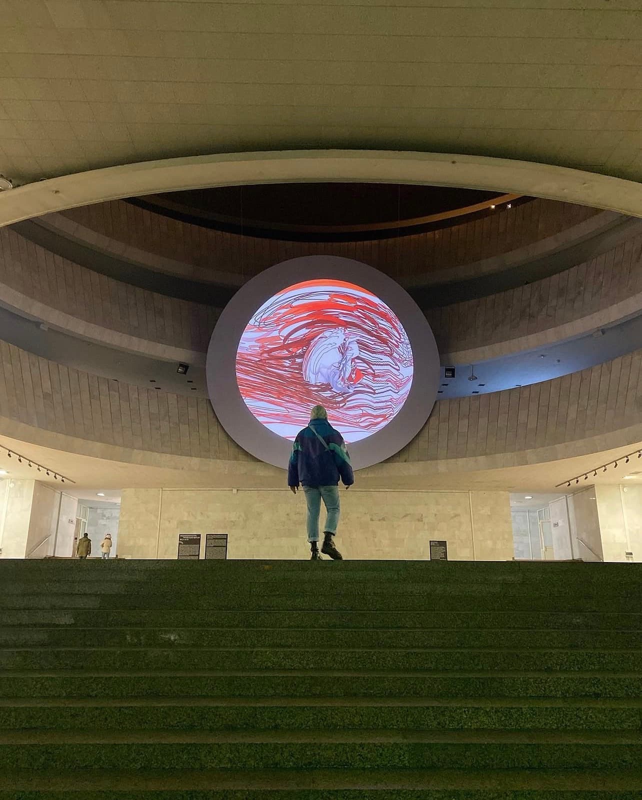 Hlib Dovzhuk standing beneath a circular video installation in a museum rotunda